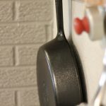 Low Tox Kitchen Swaps a cast iron pan hanging on a wall