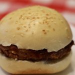 Sourdough Hamburger Buns with a burger patty on a picnic table