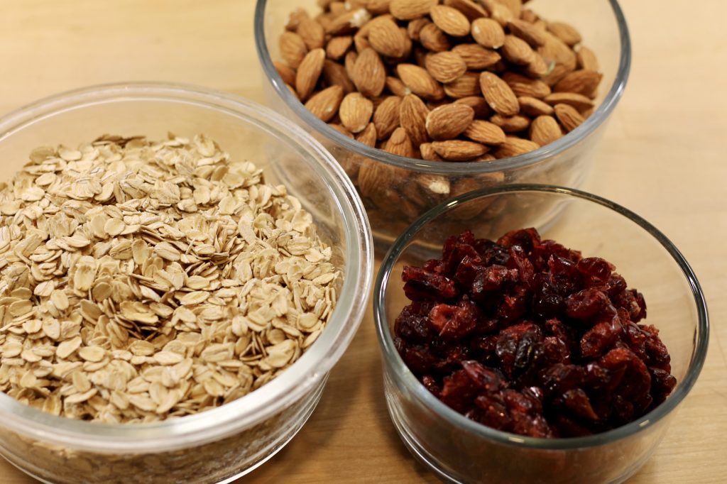 oats, dried cranberries, and almonds in glass bowls