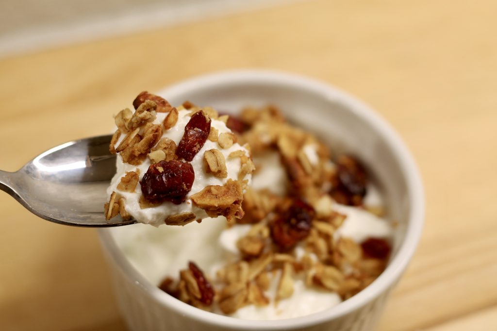 Sourdough Cranberry Almond Granola on a spoon above a bowl
