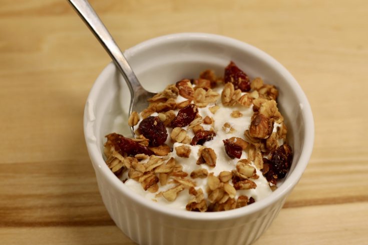 Sourdough Cranberry Almond Granola on top of yogurt with a spoon