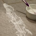 Homemade Grout Cleaner being applied with a toothbrush on gray tile floors
